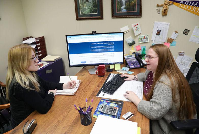 A female financial aid counselor helps a female student in her office